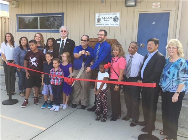 Photo of several adults and four elementary students at a ribbon cutting in front of a modular building